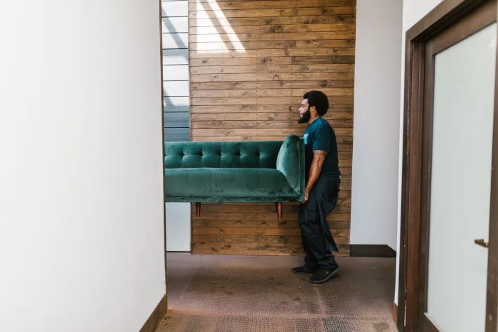 A crew carrying a couch out for furniture removal